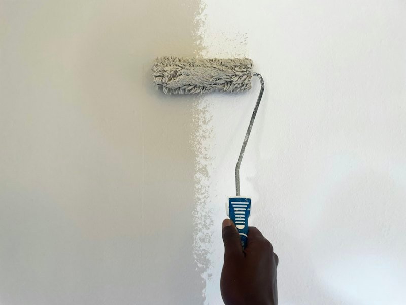 Hand streicht eine Wand mit der Farbrolle